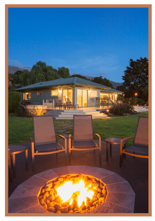 Stylish outdoor kitchen with a grill, wooden countertops, and lush greenery in the background