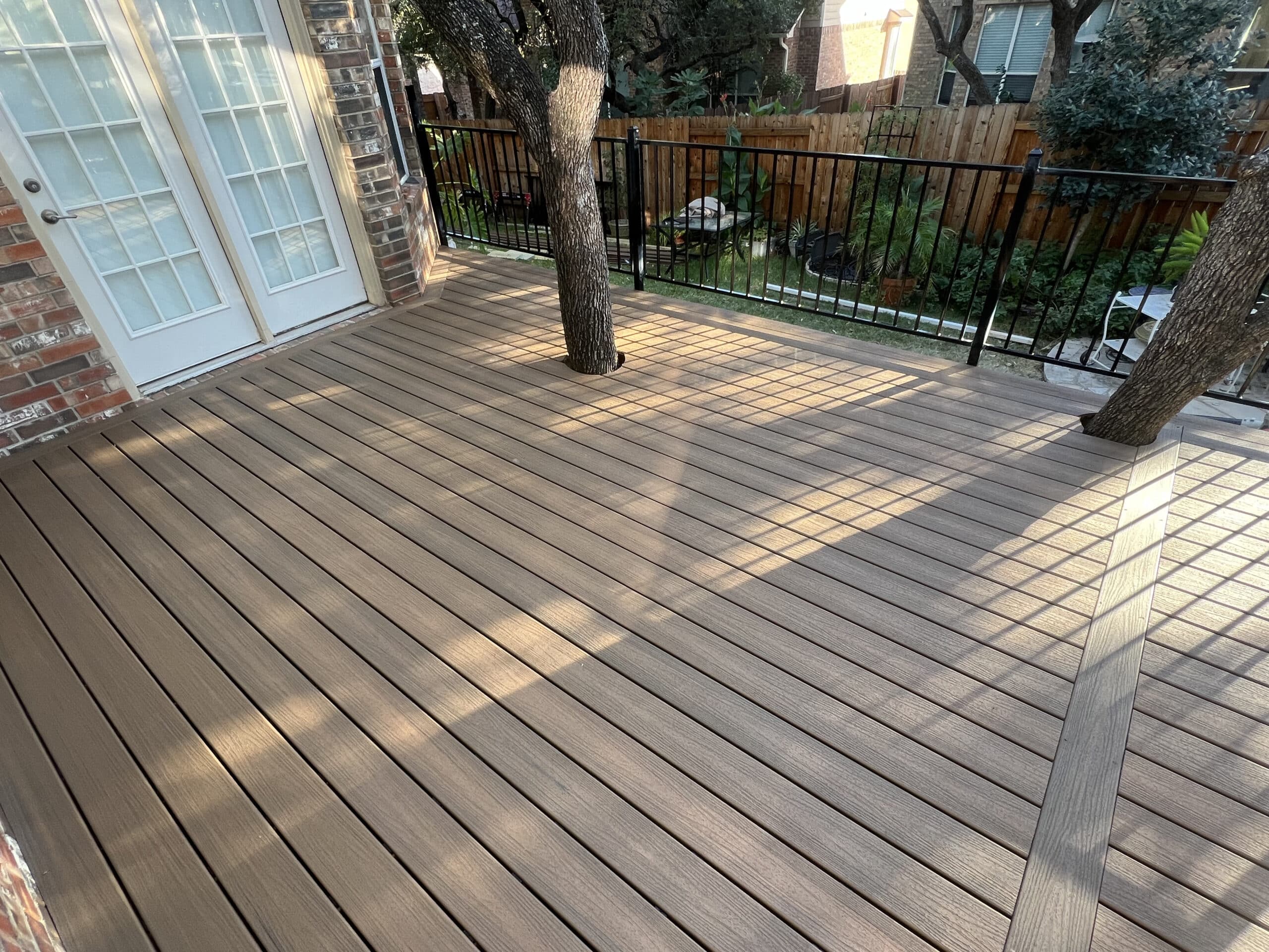 Spacious brown composite deck with tree cutouts and railing, showcasing a low-maintenance outdoor space