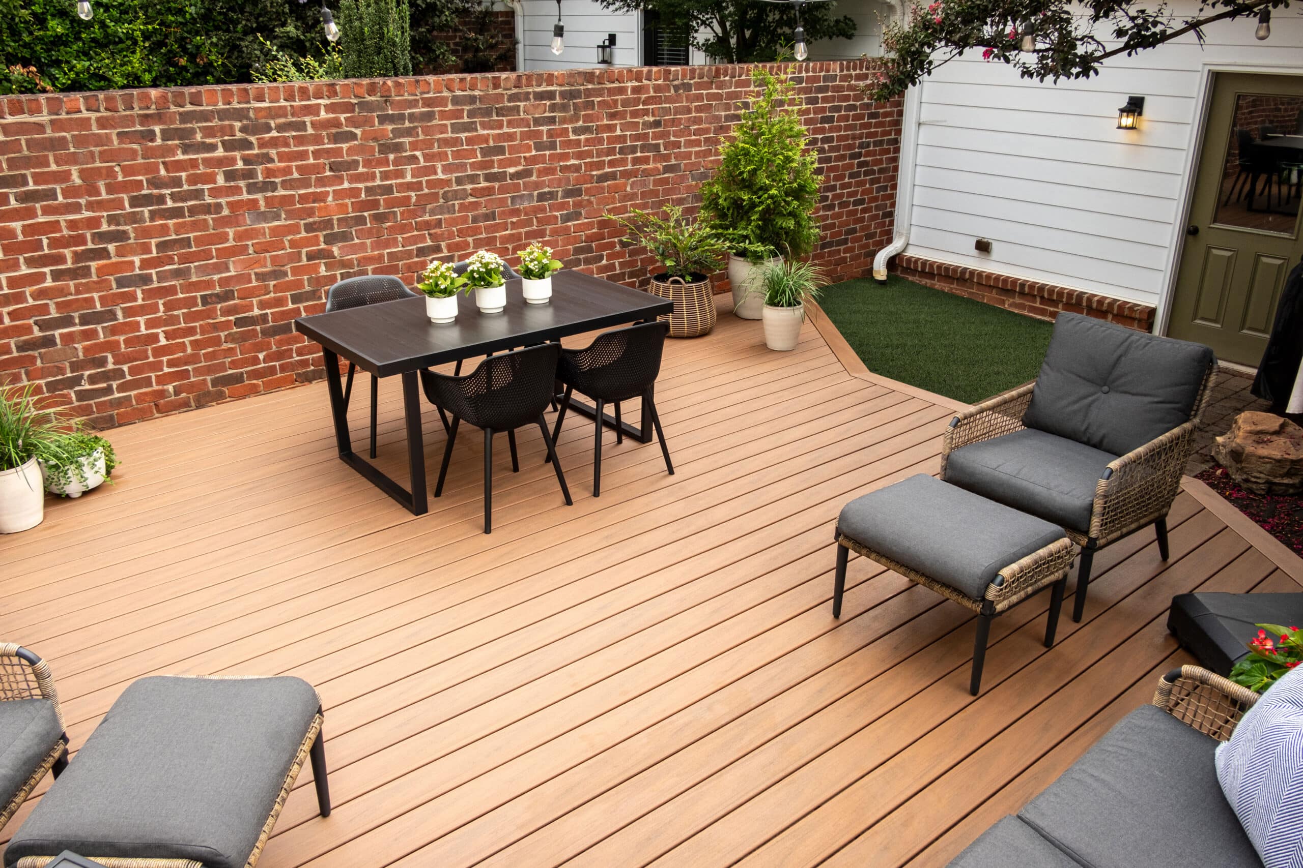 Enclosed backyard with honey-colored TREX composite decking and modern black furniture