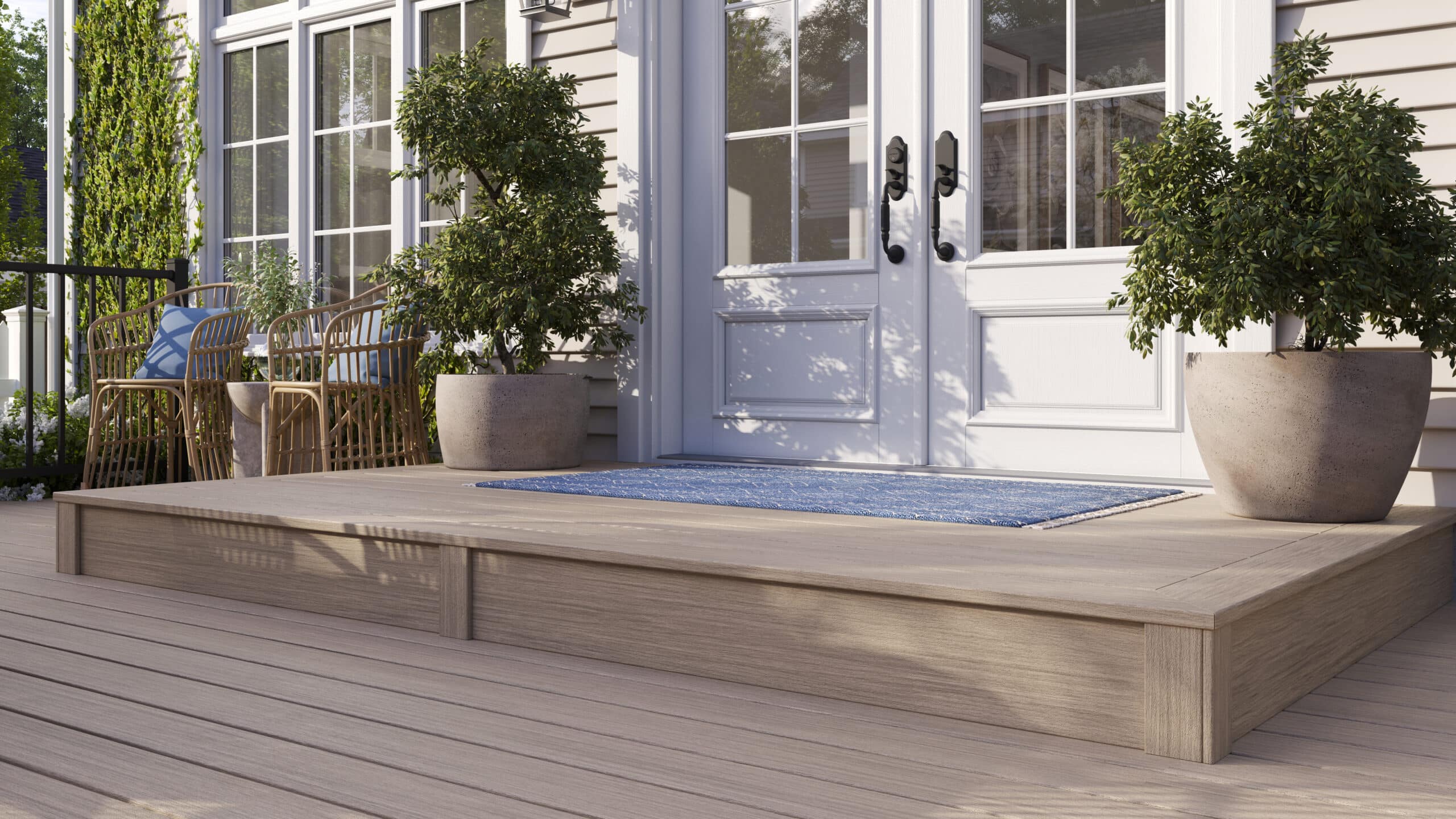 Light-colored TREX composite decking at a front porch entryway with potted plants and white doors